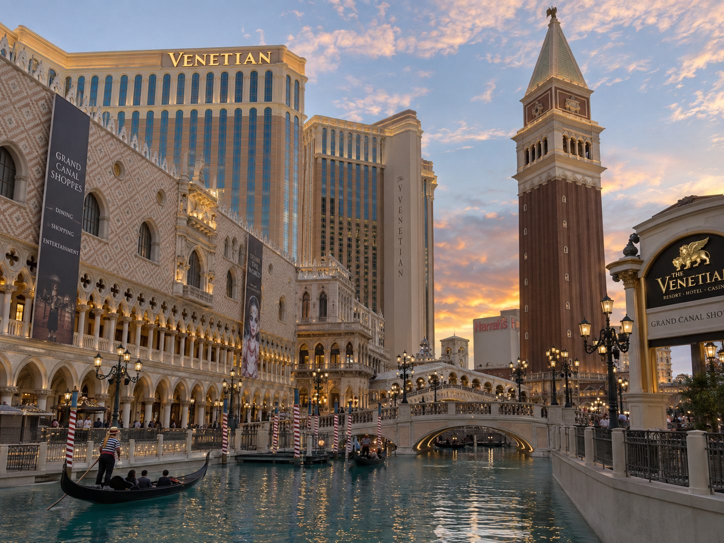 Gondolas glide on a replica canal beneath the Venetian's bell tower and Rialto bridge at sunset