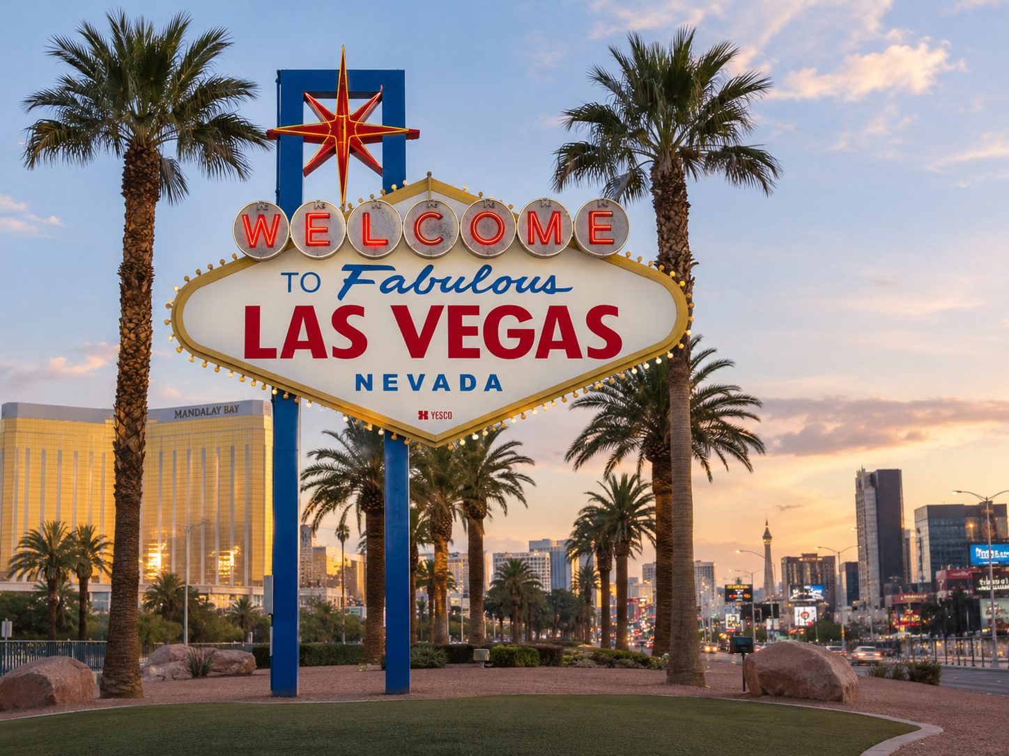 Welcome to Fabulous Las Vegas sign flanked by palm trees at dusk with skyline behind